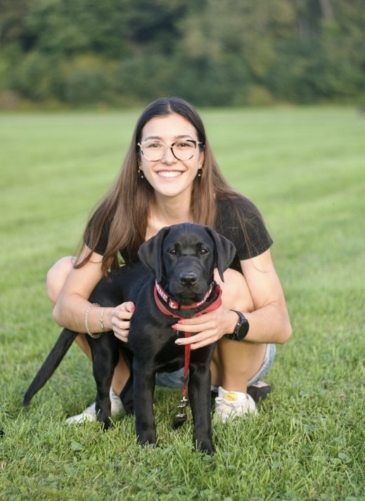 A portrait of Stacy Kaneko with black lab puppy.